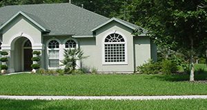 A photo of a Florida home. Its landscape features a grassy lawn in front.