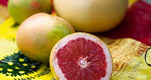 A close up photo of grapefruit arranged on a bag with a grower label. A half-grapefruit showing the pink interior faces the camera.