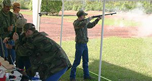 A person shooting a flintlock rifle at a youth shooting tournament.
