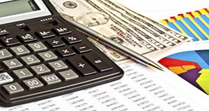 close-up photo of calculator, cash, pen and spreadsheet printout