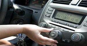 A photo of the center console of a car dashboard, with a hand turning a dial.