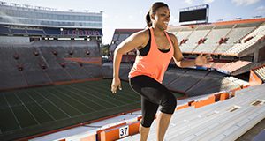 Woman in exercise clothes running up stadium steps.
