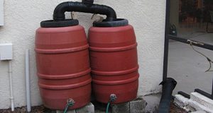 two rain barrels against the wall of a house