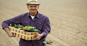 photo of smiling agricultural worker holding a basket of vegetables