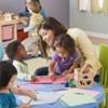 A woman sitting at a table with a group of children.