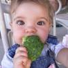 Esta niña de dos años de edad está disfrutando de su merienda brócoli.