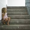 A barefoot little girl sitting on stairs.