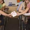 Kids passing a love note in class.