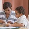 A mother sitting at the table and helping her son with homework.