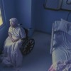 An elderly woman sitting in a wheelchair in a dark room.