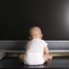 A baby sitting in front of a big screen TV.
