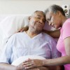 An older couple embracing in a hospital room.