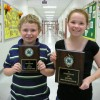 Two children holding up 4-H plaques.