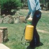 Alguien que usa un pulverizador de bomba manual para aplicar pesticida diluido en agua alrededor de un césped y jardín.