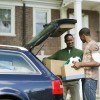 A young adult unpacking a car with his father.