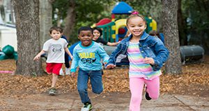 Children running toward the camera with a playground in the background