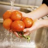 Hands rinsing off tomatoes.