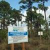 A sign in front of a forest.