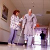 Nurse helping an old man on crutches.
