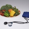 Plate of vegetables next to a blood pressure cuff and monitor