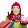 A woman in winter clothes holding giftbags in one hand and a piggy bank in the other.
