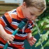 Young boy drinking water from hose