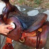 A dirty saddle being “scrubbed” using saddle soap and water.
