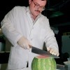 Food worker cutting watermelon