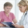 A woman looking over information on a clipboard with her doctor