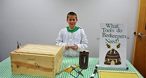 A young boy doing a presentation on the tools beekeepers need.