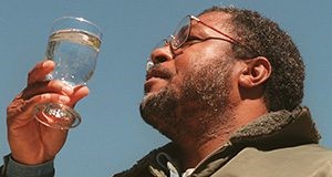 A man examining a glass of water in the sunlight.