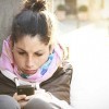 A young woman looking distressed and typing on her phone.