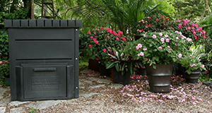 Backyard composter with potted flowers and trees.