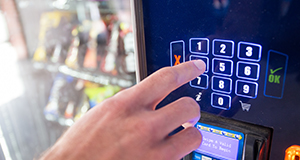 Hand on keypad using a vending machine.