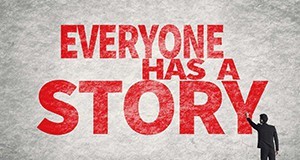 Man spray painting bold, red text that reads, "everyone has a story."