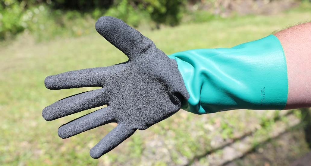 A hand wearing a nitrile glove with a textured grip.