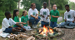 4-H members and volunteer at campfire eating s'mores.