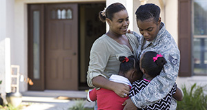 Active duty military mother hugs her three daughters in front of their home. Image used in the 2015 UF/IFAS Extension Calendar. Credits: UF/IFAS.