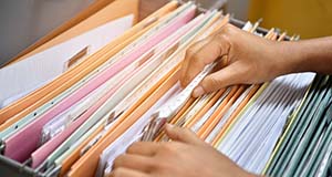 Person looking through records in filing cabinet. 