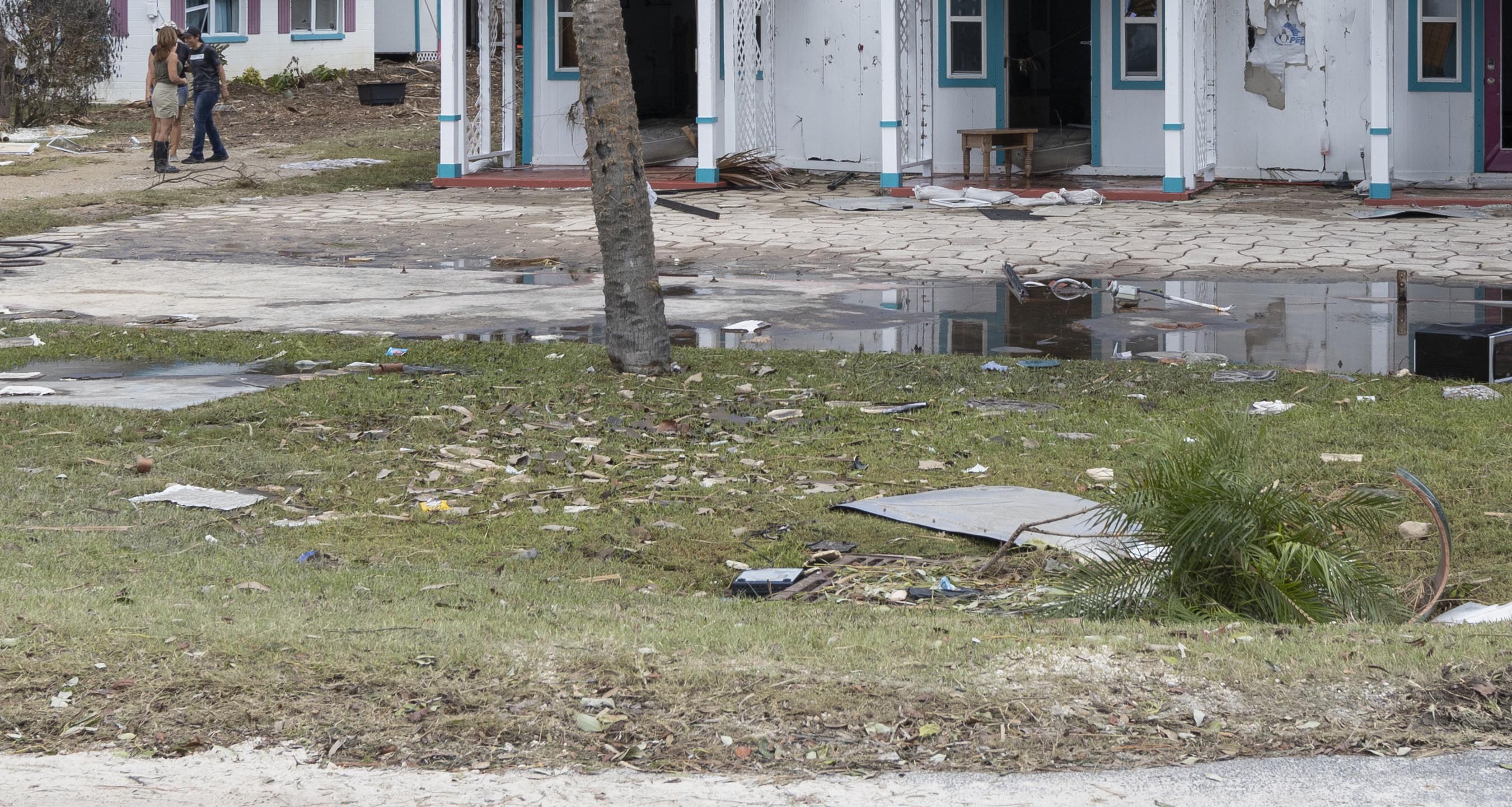 Plant, metal, and other miscellaneous debris and flooding on lawn in Cedar Key Florida after Hurricane Idalia.