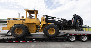 A tractor for clearing debris being loaded onto a flatbed trailer. Photo taken 08-29-23. UF/IFAS Photo by Tyler Jones.